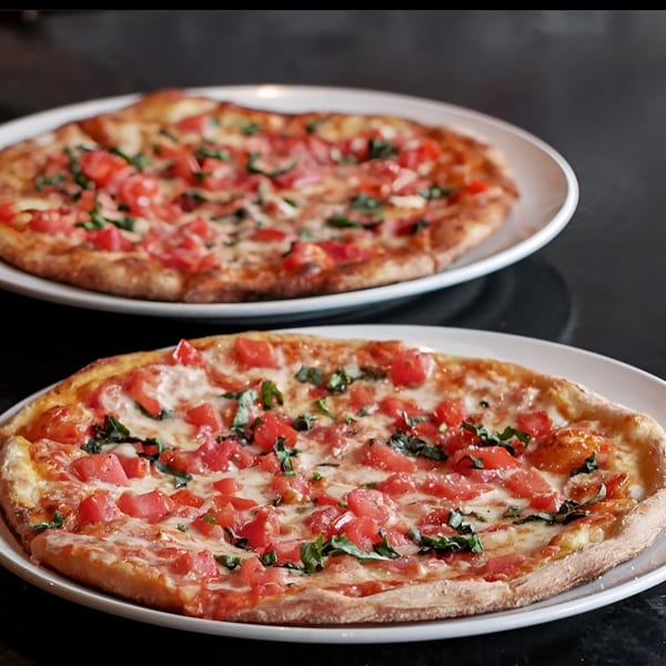 Two freshly baked Esposito's Pizza Bar Margherita pizzas with diced tomatoes and basil.
