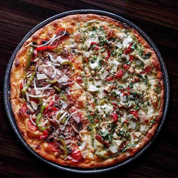 Esposito's half-and-half pizza with red sauce, peppers, and onions on one side, and pesto with chicken on the other.