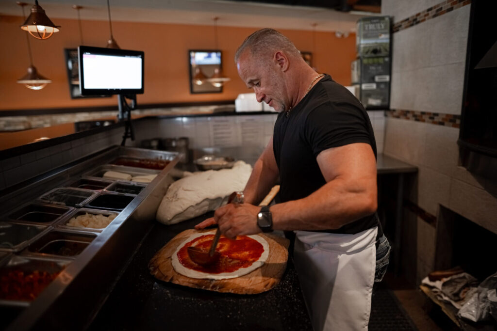 chef spreading marinara sauce on fresh pizza dough at Espositos Pizza Bar and Restaurant